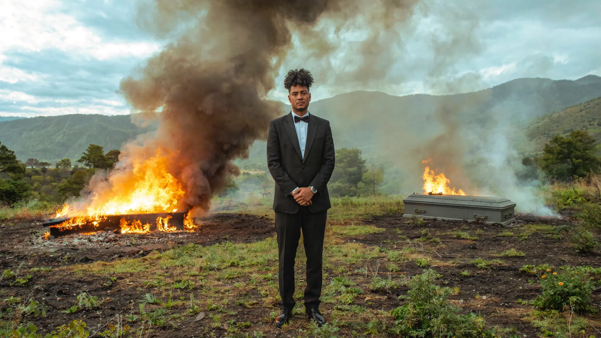 Sled em cena de clipe, de terno, com fogo ao fundo